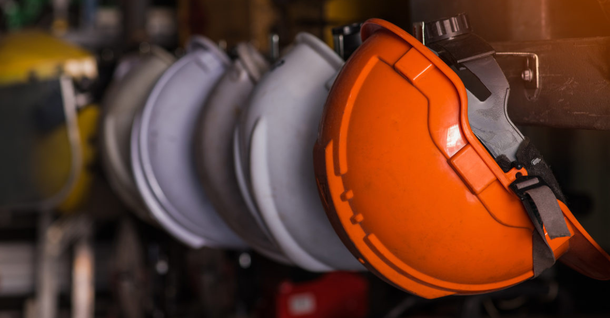 Row of construction safety helmets hanging on hooks, representing site safety equipment and general labouring work.