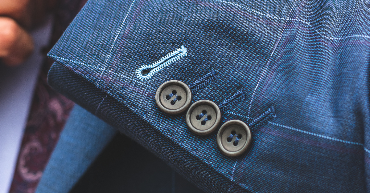 Close-up of a tailored suit sleeve with button detailing, representing a professional legal role.